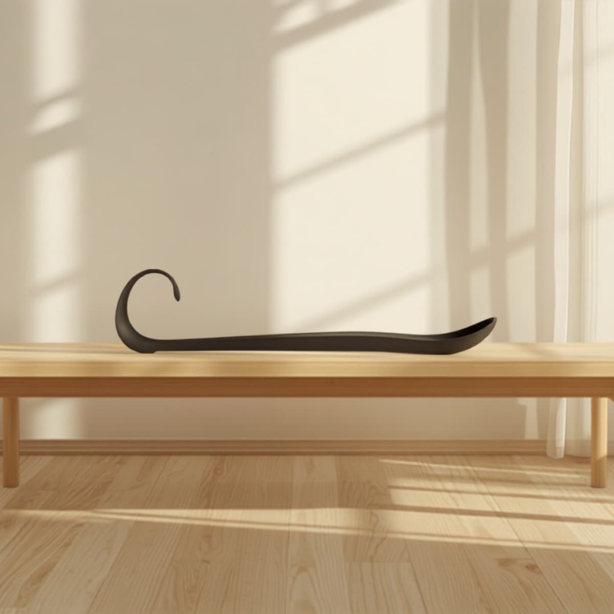 Chausse-pied long Aides Autonomie posé sur un banc en bois clair dans une chambre lumineuse