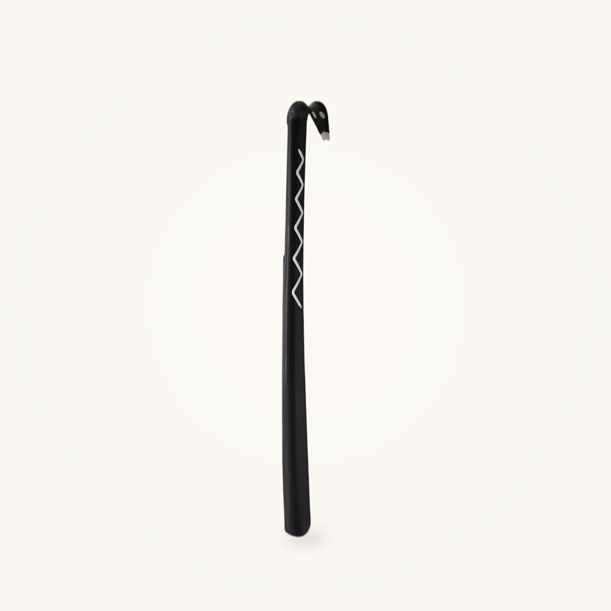 Chausse-pied long en aluminium de 60 cm posé debout contre un mur clair